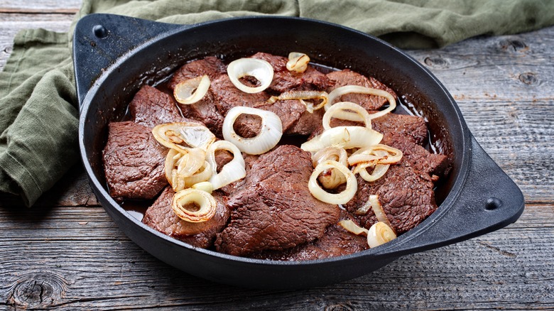 Filipino bistek tagalog resting in a cast iron dish