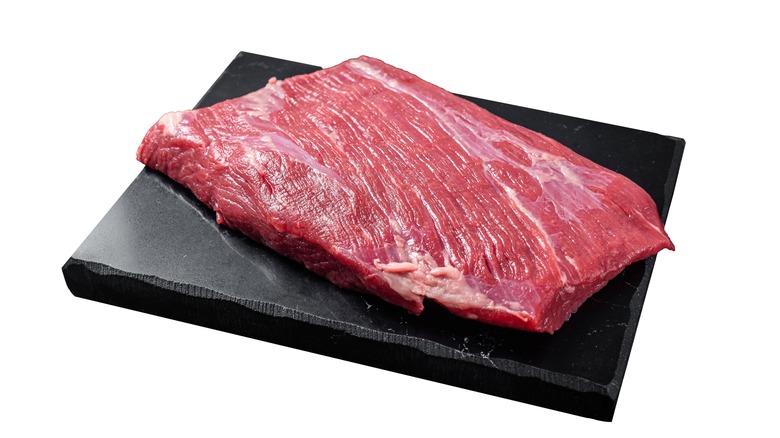 Uncooked flank steak resting on a cutting board