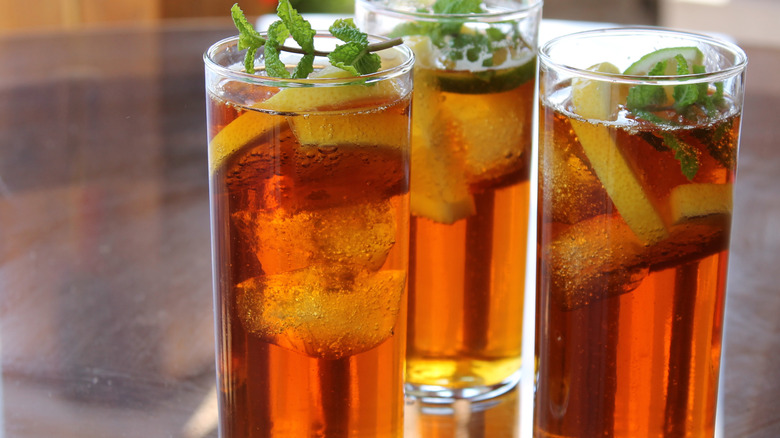 Glasses of a whisky long drink are topped with lemon slices and mint.