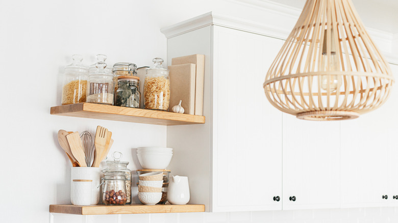 A bright white kitchen cabinet with wooden open shelving