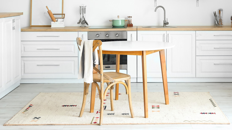 A white kitchen with a neutral dining rug and linens