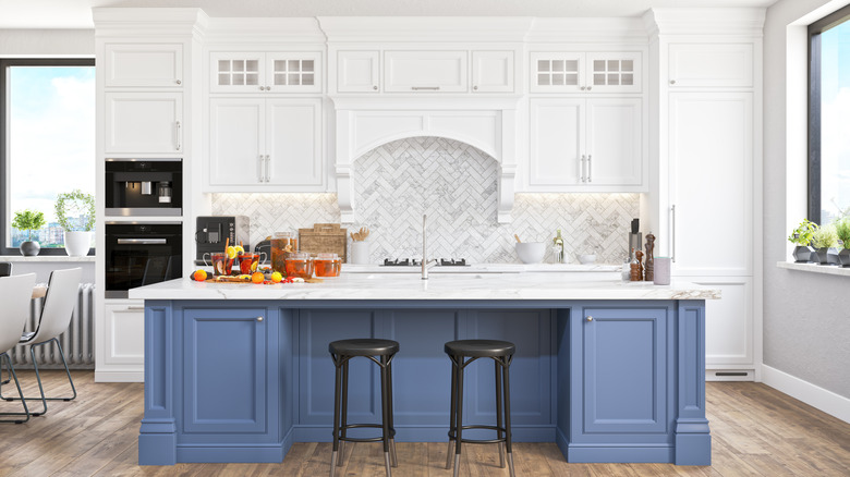 A primarily white kitchen with a blue island
