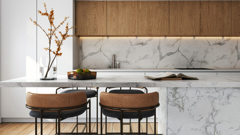 A modern kitchen with veined white countertops and backsplash