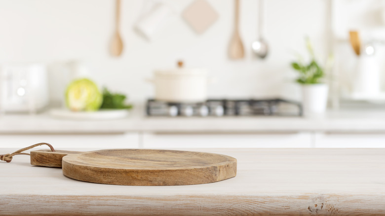 A primarily white kitchen with a wooden cutting board