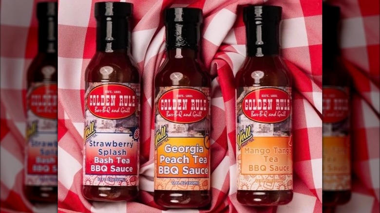 Three bottles of barbecue sauce in different Y'all sweet tea flavors, including strawberry, peach, and mango