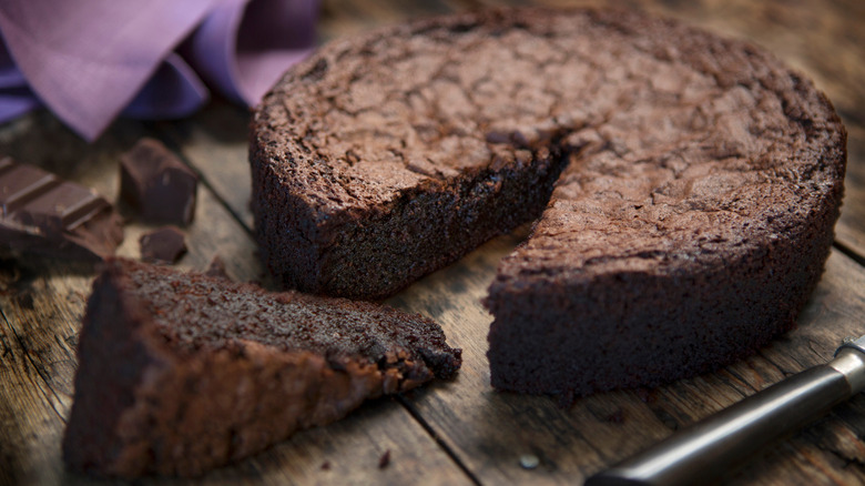 Chocolate cake with a slice removed on a wooden table