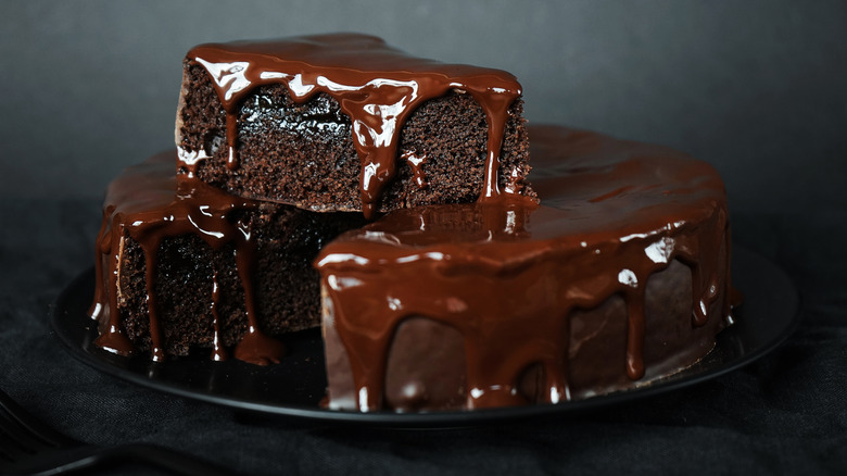 A chocolate cake oozing with frosting on a black plate