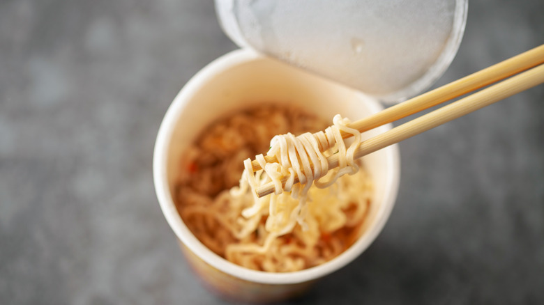 A cup of instant ramen with chopsticks