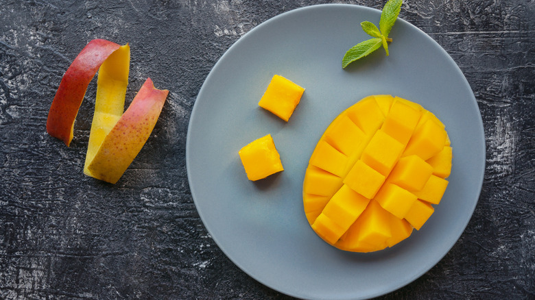 A slice of peeled mango on plate with peel curled near