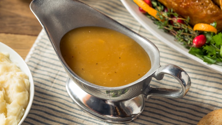 Silver gravy boat surrounded by mashed potatoes and turkey