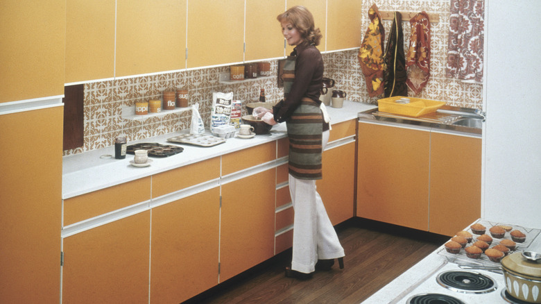 A woman stands in a 1970s-era kitchen