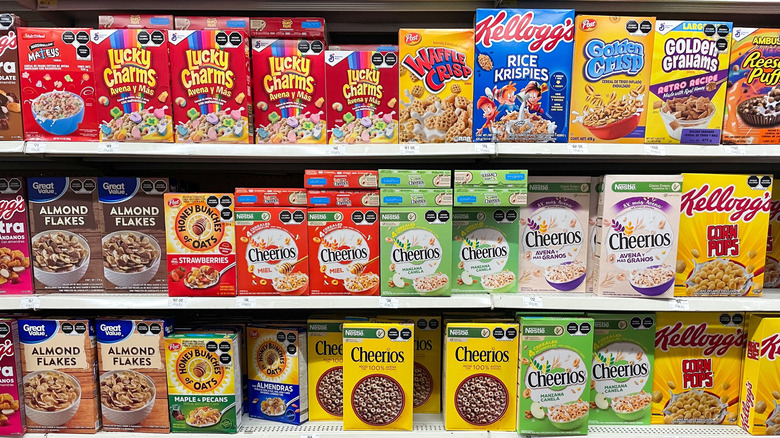 Various brands of cereal sit on a section of supermarket shelves