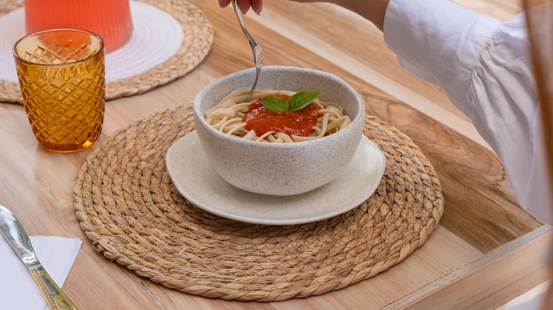 A bowl of pasta on a wicker straw rattan placemat