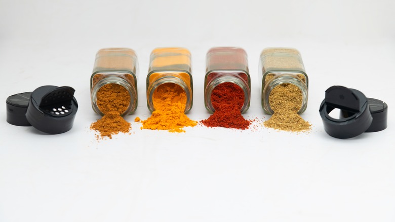 Spilled herbs and spices with lids removed from bottles