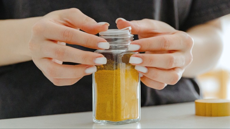 Person replacing plastic sifter cap on spice jar