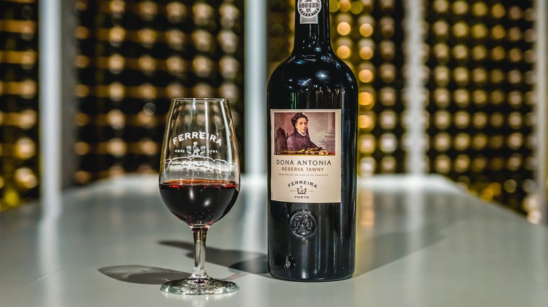 Glass and bottle of port on a table in a wine cellar