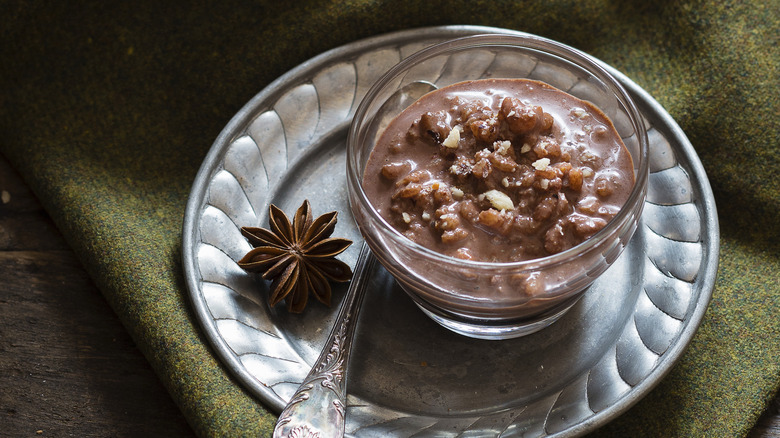 Chocolate rice pudding sits in a bowl on a plate with a star anise