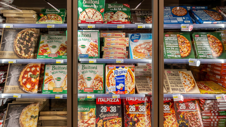 frozen pizzas in the grocery store refrigerator