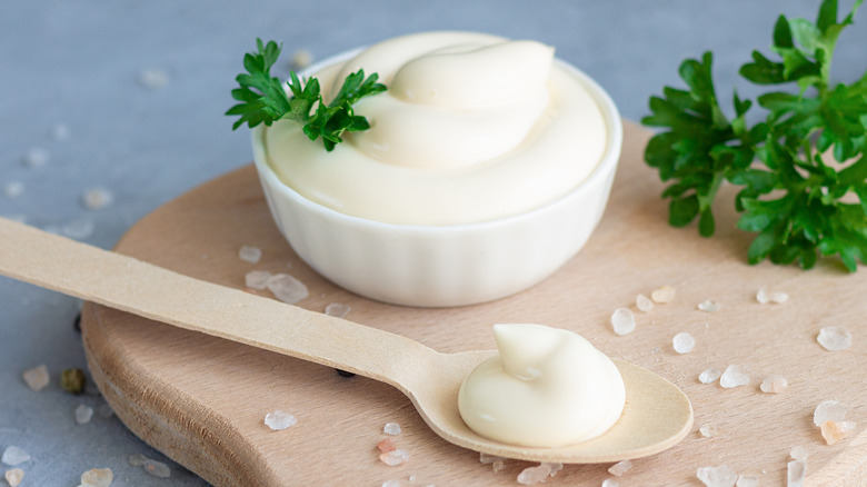 Bowl of mayonnaise on cutting board with spoon