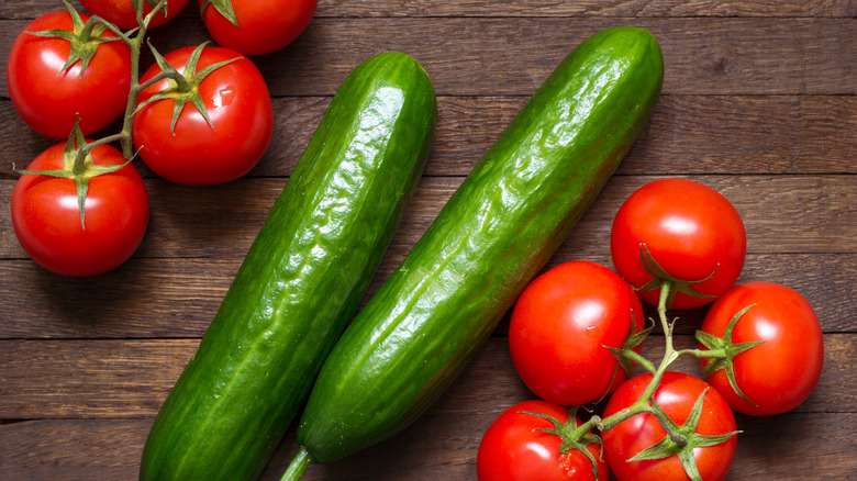Raw tomatoes and cucumbers next to each other on a table