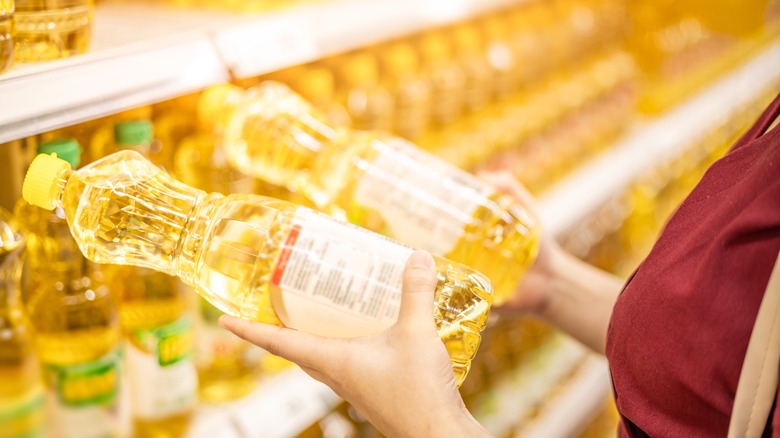 Shopper considers two bottles of vegetable oil 