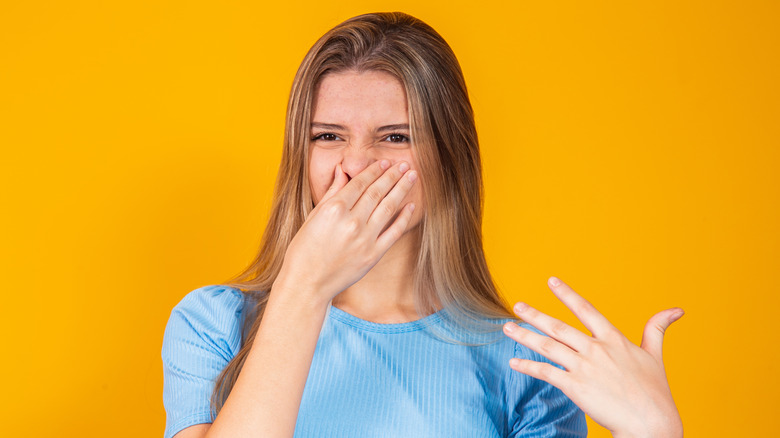 Young person covering their nose on a yellow background