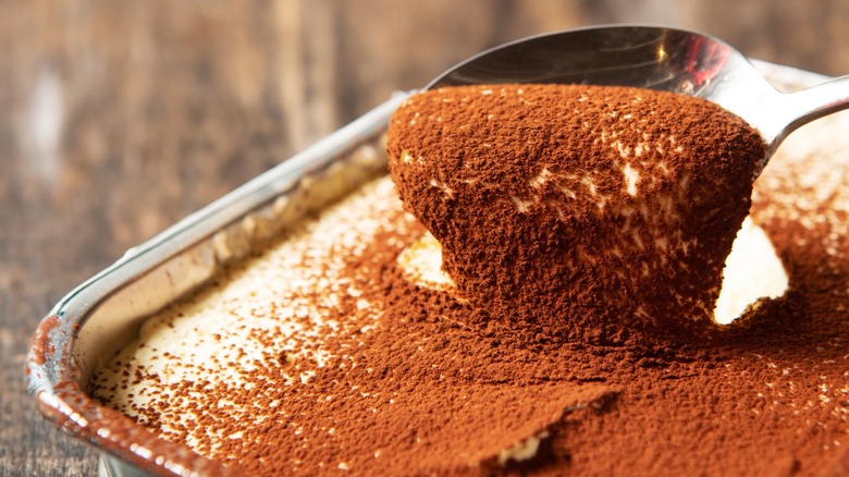 Spooning out tiramisu from a pan.