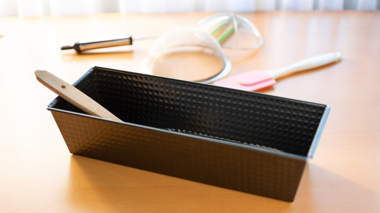 Baking utensils in and around a bread pan.