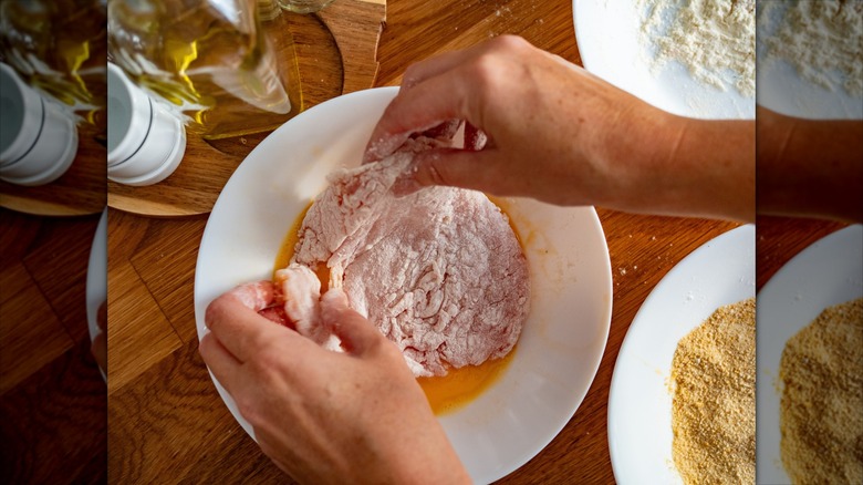 Dipping a cutlet in egg wash to make schnitzel