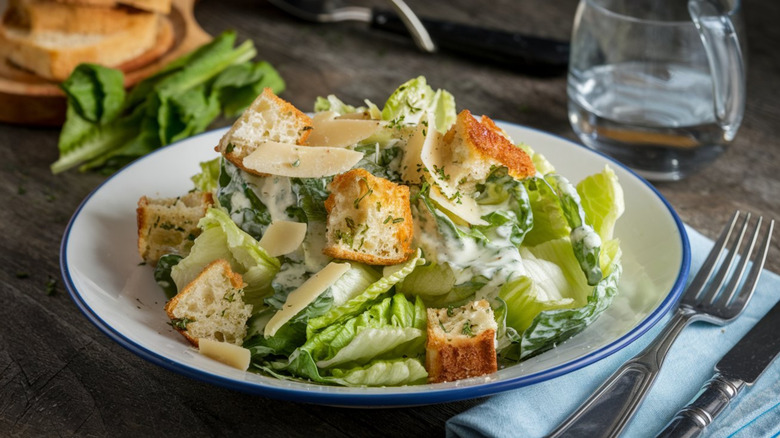 Caesar salad with large croutons and shaved Parmesan in a white bowl