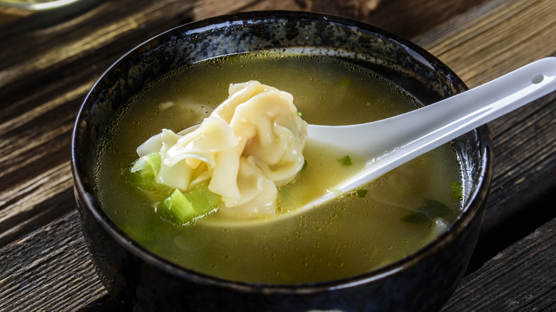 spoon in brothy wonton soup