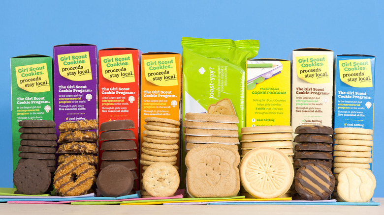 A variety of Girl Scout cookies stacked in front of their boxes