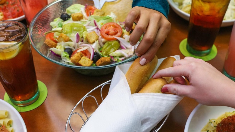 People reaching for breadsticks at Olive Garden