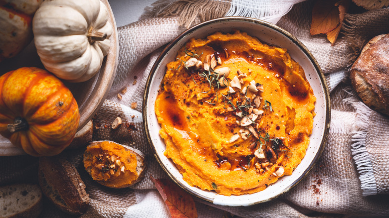 orange hummus surrounded by pumpkins