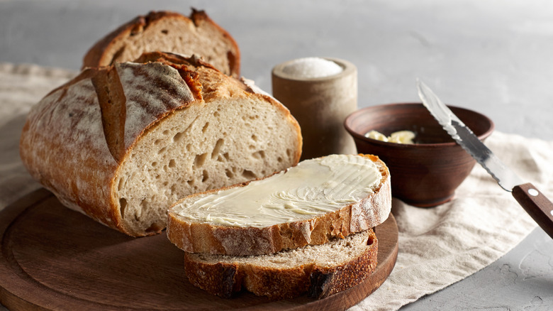 Loaf of bread with slice slathered with butter