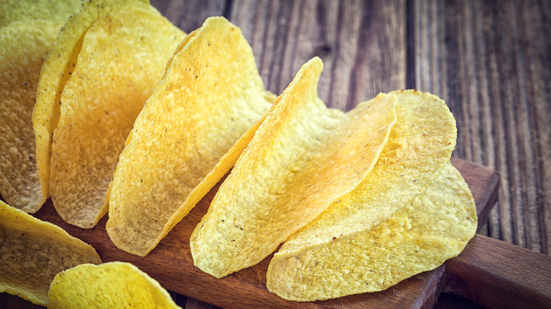 Empty yellow corn tortilla taco shells on wood cutting board
