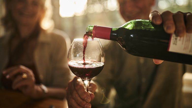 Pouring glass of red wine from bottle