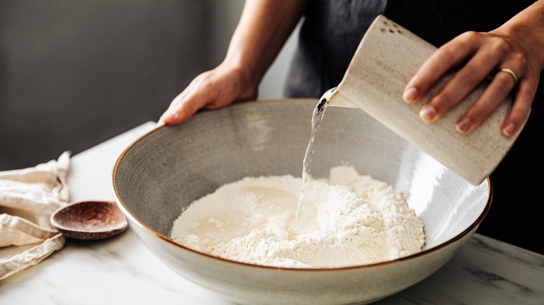 Pouring water in bowl of flour