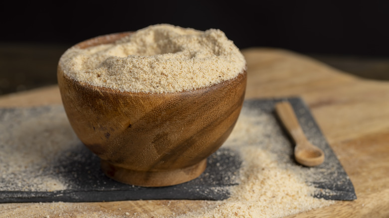 A wooden bowl of breadcrumbs, with a small wooden spoon