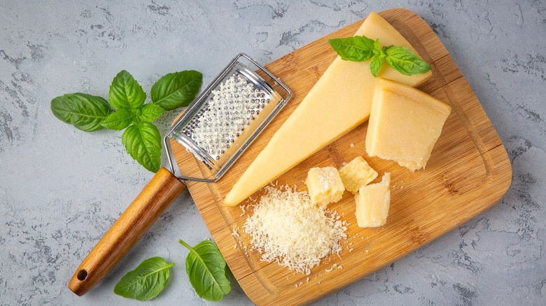 Freshly grated Parmesan cheese, with a grater, on a wooden board