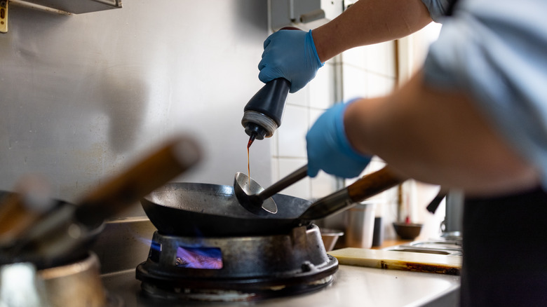 Soy sauce being added to stir fry wok