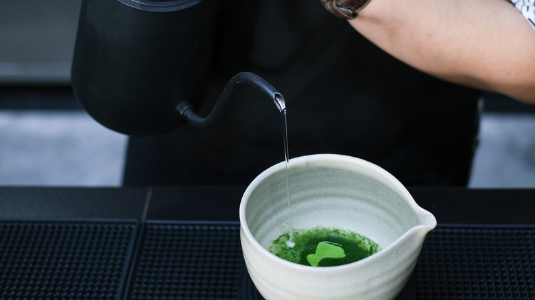 Hot water being poured onto cup of matcha powder