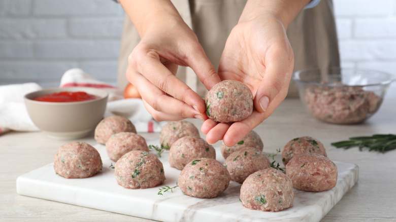 Person's hands forming raw meatballs