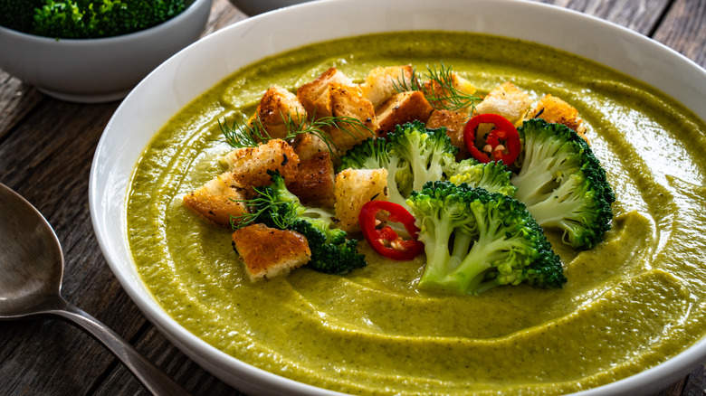 Broccoli soup garnished with broccoli, red chile slices, and croutons.