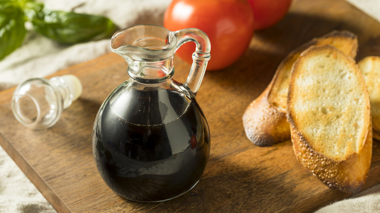 Balsamic vinegar next to tomatoes and bread